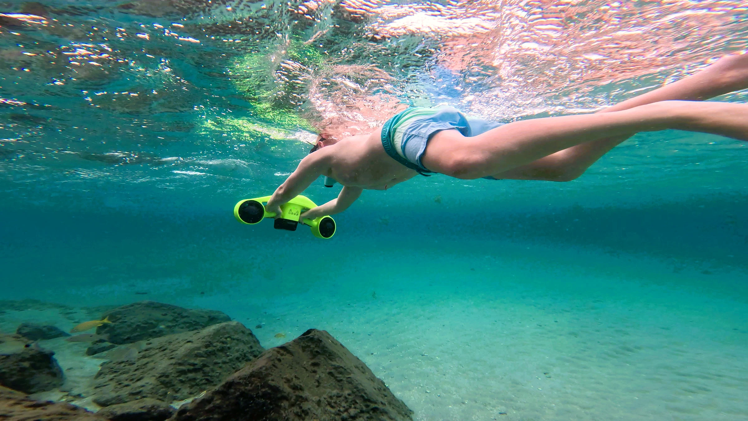 Guest snorkeling underwater with a sea scooter in clear shallow water